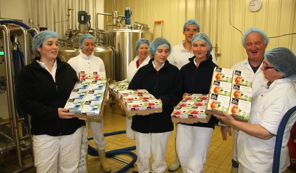 Photos duo personnel dans l’usine tenant des cartons de yaourts 